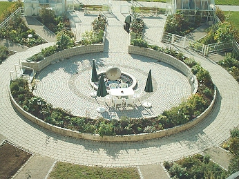 Blick vom Hausdach des Curanums, auf das sich Gartenleiter Bernhard Koesler wieder einmal gewagt hatte, um einen guten Blick auf den Zentralbereich des Gartens mit dem Weltkugel-Brunnen, das ringfoermige Hochbeet und die strahlenfoermigen Außenbeete zu erhalten.